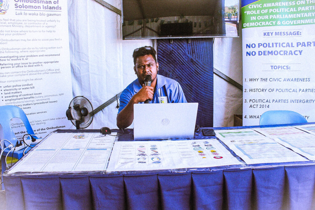Civic awareness facilitator speaking at a public information display table.